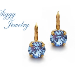 Puede incluir: Un par de pendientes de oro con piedras redondas de cristal azul claro.