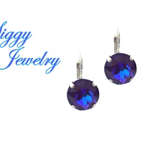 May include: A pair of silver earrings with a round, dark blue gemstone in the centre of each earring.