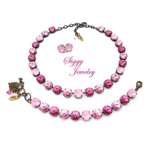 Pode incluir: Um conjunto de colar e pulseira rosa e ouro rosa com um fecho em forma de cora&ccedil;&atilde;o. O conjunto apresenta um degrad&ecirc; de cristais rosa.