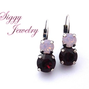 May include: A pair of silver dangle earrings with two-toned crystals. The top crystal is a light pink opal and the bottom crystal is a deep burgundy red.