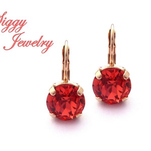 Puede incluir: Un par de pendientes de tono dorado con piedras redondas de cristal rojo. Los pendientes tienen un cierre de palanca.