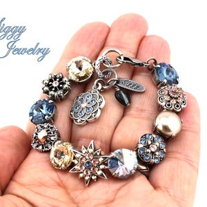 May include: A silver charm bracelet with a variety of charms, including a star, a flower, and a pearl. The bracelet also has a tag that says "Siggy Jewelry".