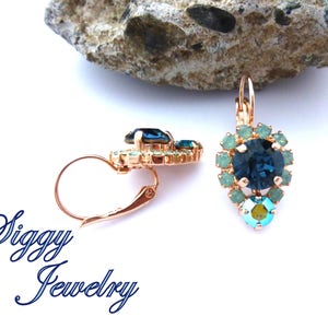 Pu&ograve; includere: Orecchini pendenti in oro rosa con un grande cristallo blu circondato da cristalli turchesi pi&ugrave; piccoli. Gli orecchini hanno una chiusura a leva.