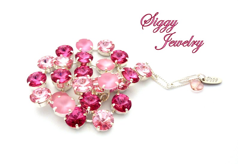 Pode incluir: Um bracelete rosa e prateado com uma variedade de contas de cristal. O bracelete tem um pequeno charme com a palavra "Siggy Jewelry" nele.