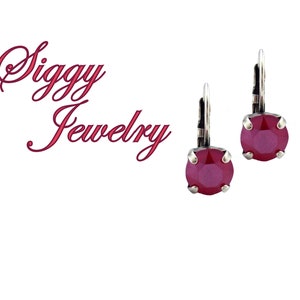 May include: A pair of silver dangle earrings with a red crystal stone. The earrings have a hook closure.