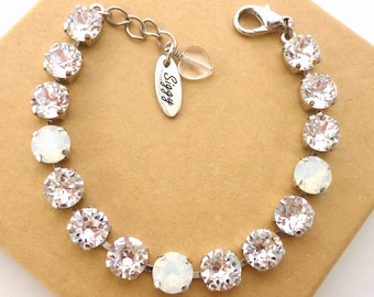 May include: A silver bracelet with clear and opal-colored crystals. The bracelet has a lobster clasp and a small heart charm with the word "Siggy" on it.