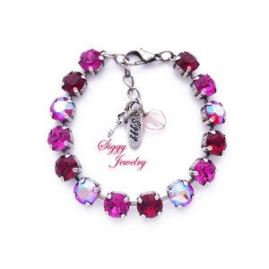 Könnte beinhalten: Ein silbernes Armband mit einer Kette und einem Anhänger mit der Aufschrift "Siggy Jewelry". Das Armband ist mit rosa und schillernden Kristallen verziert.