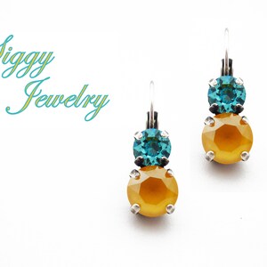 May include: A pair of dangle earrings with a yellow and teal crystal design. The earrings have a silver hook.