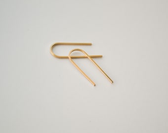 May include: A pair of gold-toned, minimalist earrings with a simple, curved shape.
