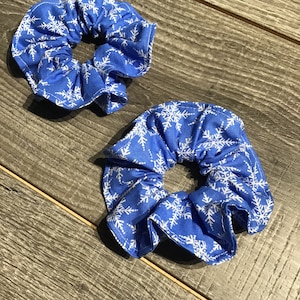 May include: Two blue scrunchies with a white snowflake pattern.
