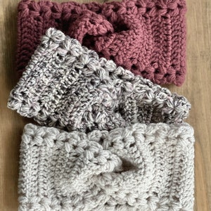 May include: Three crocheted headbands in different colors and patterns. The top headband is a deep burgundy, the middle headband is a light gray with a speckled pattern, and the bottom headband is a light beige.