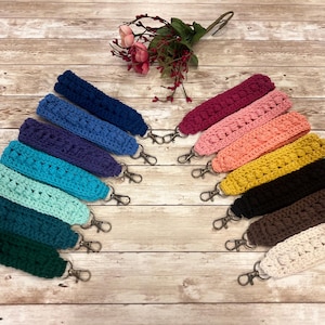 May include: A set of 10 crocheted keychains in various colors, including blue, green, pink, yellow, and brown. Each keychain has a metal ring attached.