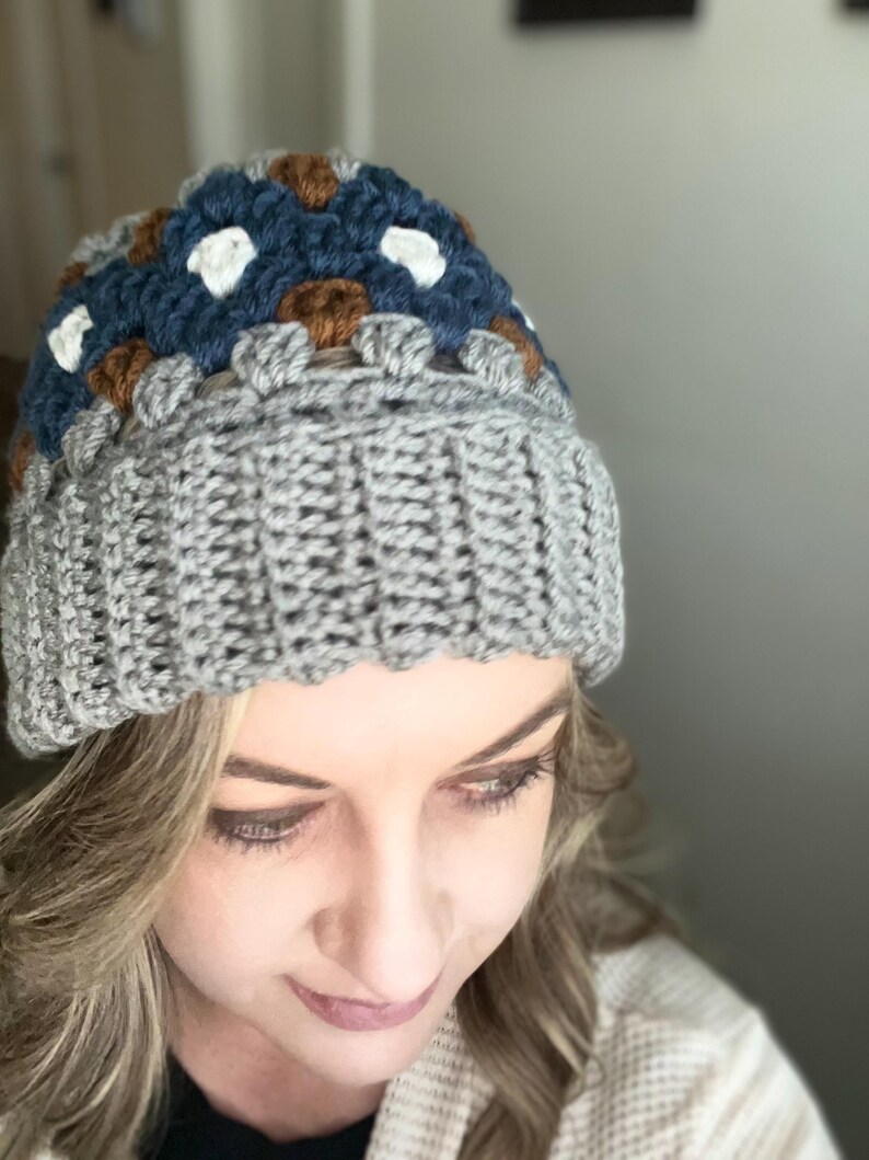 May include: A grey crocheted beanie with a brown, white and blue geometric pattern on the top.