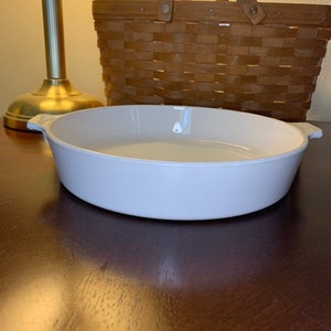 May include: White ceramic baking dish with two handles. The dish is oval shaped and has a smooth, glossy finish.