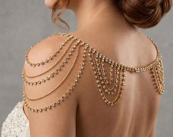 May include: A gold shoulder necklace featuring multiple strands of delicate chains and sparkling rhinestones. The jewellery drapes over the shoulders and back, creating a glamorous and elegant look. Ideal for weddings or special occasions.