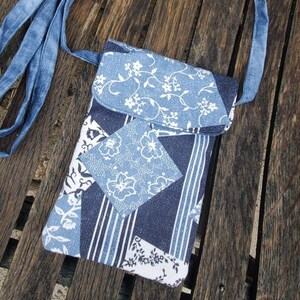 May include: A blue denim crossbody bag with a flap closure. The bag features a patchwork design with floral and striped patterns in shades of blue and white. The strap is made of the same denim material.
