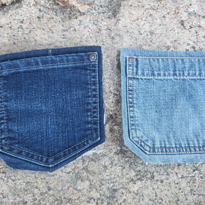 Pu&ograve; includere: Due tasche di jeans in denim. Una &egrave; di un lavaggio blu scuro, l'altra &egrave; di un lavaggio blu chiaro. Entrambe le tasche hanno una forma rettangolare con il fondo curvo e sono cucite con un filo a contrasto. La tasca blu scuro ha un bottone argentato.
