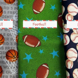 May include: Three fabric swatches with different sports themes. The first swatch is gray with a basketball pattern and the words "Basketball, Jump Shot, Dribble, Motivation, 3 Point". The second swatch is green with a football pattern and blue stars. The third swatch is navy blue with a baseball pattern and the word "Baseball".