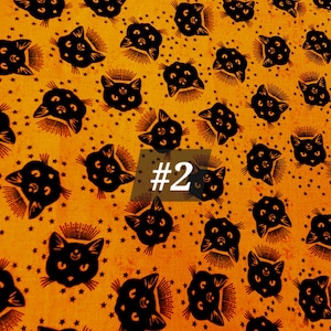 May include: Orange fabric with a repeating pattern of black cats with three eyes and a crescent moon. The cats are surrounded by small stars. The text '#2' is visible in the centre of the image.