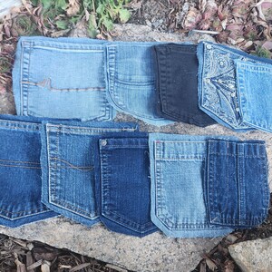 Pu&ograve; includere: Una collezione di tasche di jeans in varie tonalit&agrave; di blu e nero, disposte su una superficie di pietra. Le tasche presentano diversi modelli di cucitura e stili, mostrando la variet&agrave; di trame e lavaggi del denim.