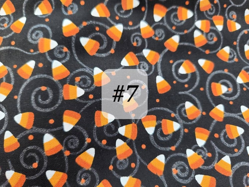 May include: Black fabric with a repeating pattern of orange and white candy corn, small orange dots, and white swirls. The number "#7" is written in white on a white square.