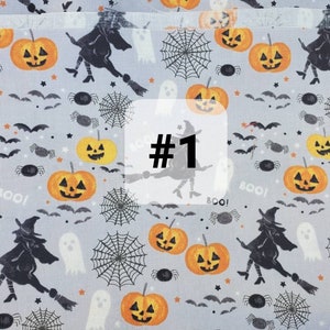 May include: A grey fabric with a Halloween theme featuring black witches, orange pumpkins, spiders, bats, and the words "Boo!" and "#1".