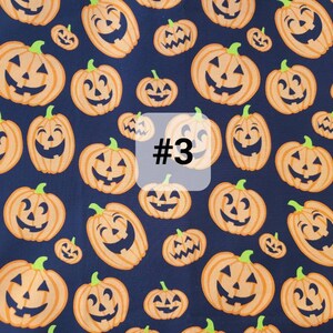 May include: A dark blue fabric with a repeating pattern of orange jack-o'-lantern faces. The fabric has the number "#3" printed on it.