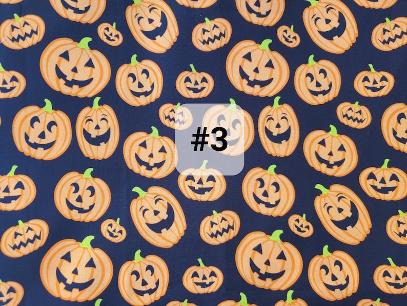 May include: A dark blue fabric with a repeating pattern of orange jack-o'-lantern faces. The fabric has the number "#3" printed on it.