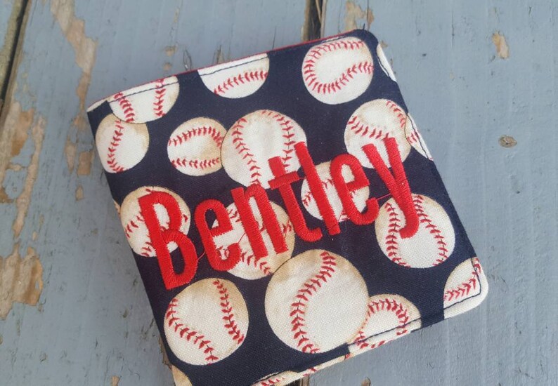 May include: A black fabric wallet with a baseball pattern and the name "Bentley" embroidered in red.