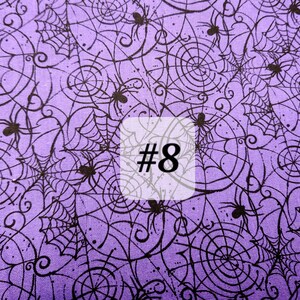 May include: Purple fabric with a black spiderweb and spider pattern. The fabric has the number 8 printed on it.