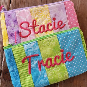 May include: Two colorful zippered pouches with patchwork fabric designs. The top pouch has the name "Stacie" embroidered in pink. The bottom pouch has the name "Tracie" embroidered in pink.