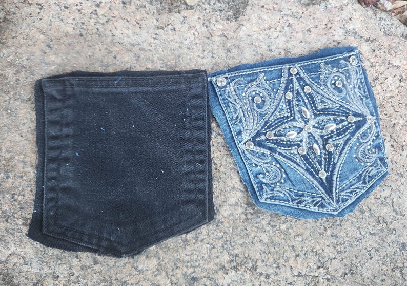 Pu&ograve; includere: Due tasche di jeans. Una &egrave; nera tinta unita, l'altra &egrave; blu chiaro con ricami bianchi intricati e abbellimenti color argento. Le tasche provengono probabilmente da jeans o da un capo simile.