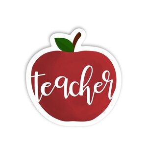May include: A red apple sticker with a green leaf and brown stem. The word "teacher" is written in white cursive script across the apple. The sticker has a white border.