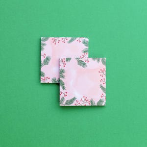 May include: Two pink sticky note pads with a green and red holly berry border.