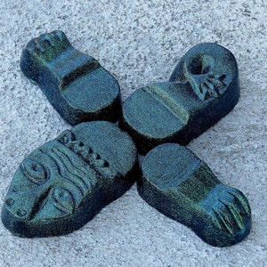 May include: A black and green glittery ceramic figurine of a creature with four limbs and a head. The creature has a textured surface and a stylized face.