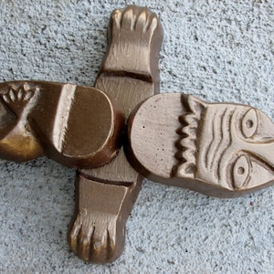 May include: A brown ceramic sculpture of a stylized animal with a face and a body. The sculpture is made of two pieces that fit together.