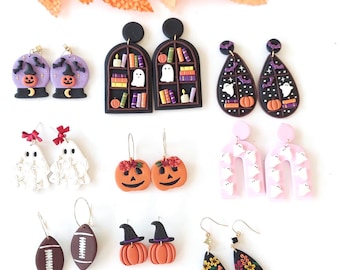 May include: A collection of Halloween-themed earrings in various designs. Includes purple snow globes with pumpkins, black arched bookshelves with ghosts, teardrop shapes with bats and pumpkins, and football-shaped earrings. Other designs include pumpkin faces and witch hats.