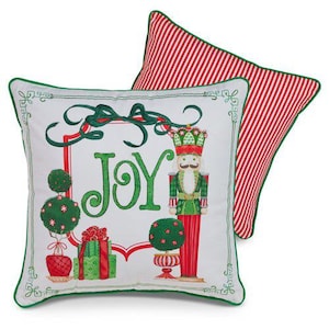 May include: Two decorative Christmas pillows. One pillow features a white background with a green border and the word "JOY" in green. The design includes a nutcracker, gifts, and topiary. The other pillow has a red and white striped pattern.