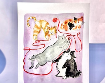 May include: A watercolour greeting card showing four cats playing with red yarn. One cat is ginger and white, another is grey, and two are black and white. The background is a soft purple.