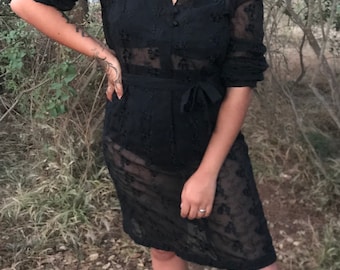 May include: A black sheer dress with a lace pattern and a tie at the waist.