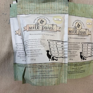 May include: A bag of Miss Mustard Seed's Milk Paint in the color Linen. The bag is white with green and yellow accents. The text on the bag reads "Miss Mustard Seed's Milk Paint" and "Move mountains in your home." The bag also includes information about the paint, such as the coverage and the fact that it is environmentally friendly and contains no VOCs.