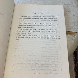 Peut inclure: Une page d'un livre vintage avec une page de titre qui lit "머리말" en cor&eacute;en. Le texte est en cor&eacute;en et en anglais et explique le but du livre, qui est d'aider les domestiques cor&eacute;ens &agrave; comprendre les fa&ccedil;ons occidentales de tenir une maison.