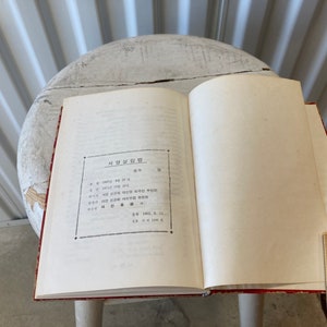 Peut inclure: Un livre ouvert avec une couverture rouge et des pages blanches. Le livre est intitul&eacute; "사명과 비전" en cor&eacute;en. Le texte sur la page est en cor&eacute;en.