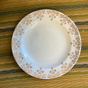 May include: A white ceramic plate with a gold floral design around the rim.