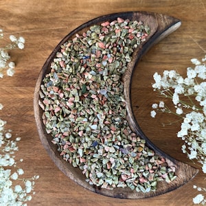 Puede incluir: Un plato de madera en forma de media luna lleno de pequeñas piedras pulidas de colores. Las piedras son una mezcla de verde, rosa y marrón.