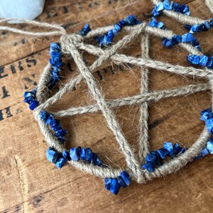 May include: A handmade dreamcatcher with a five-pointed star design, woven with natural twine and accented with blue lapis lazuli stones.