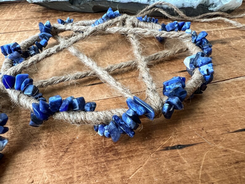 May include: A blue and white crystal dreamcatcher with a jute rope base. The crystals are arranged in a circular pattern around the rope.