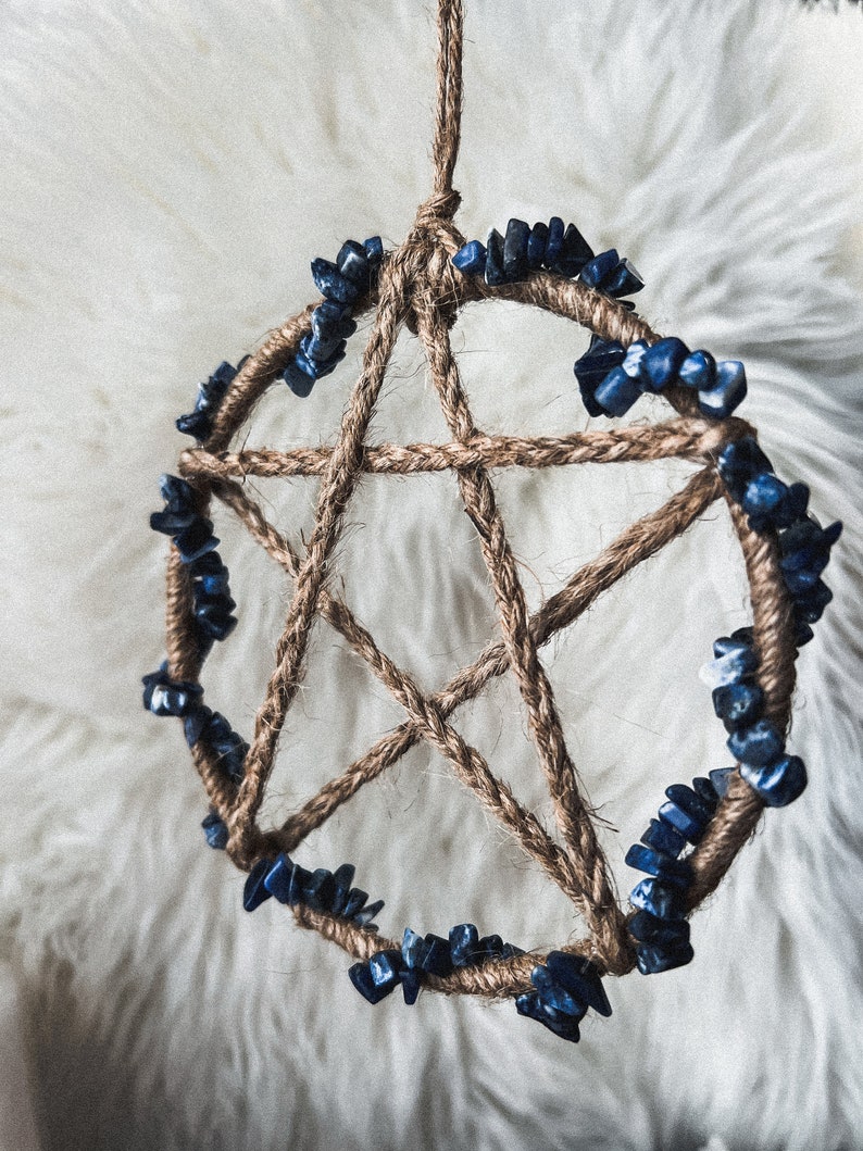 May include: A brown rope pentagram with blue lapis lazuli stones woven into the rope.