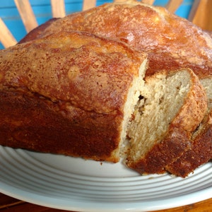 May include: A loaf of freshly baked bread sliced on a white plate. The bread is golden brown and has a slightly crispy crust.