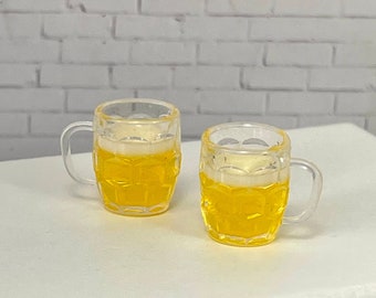 May include: Two clear glass beer mugs filled with a yellow liquid, sitting on a white table.